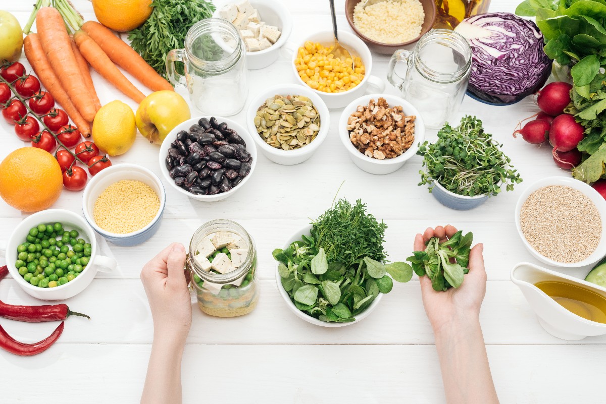 Cropped View Of Woman Adding Herbs In Jar With Salad On Wooden White Table